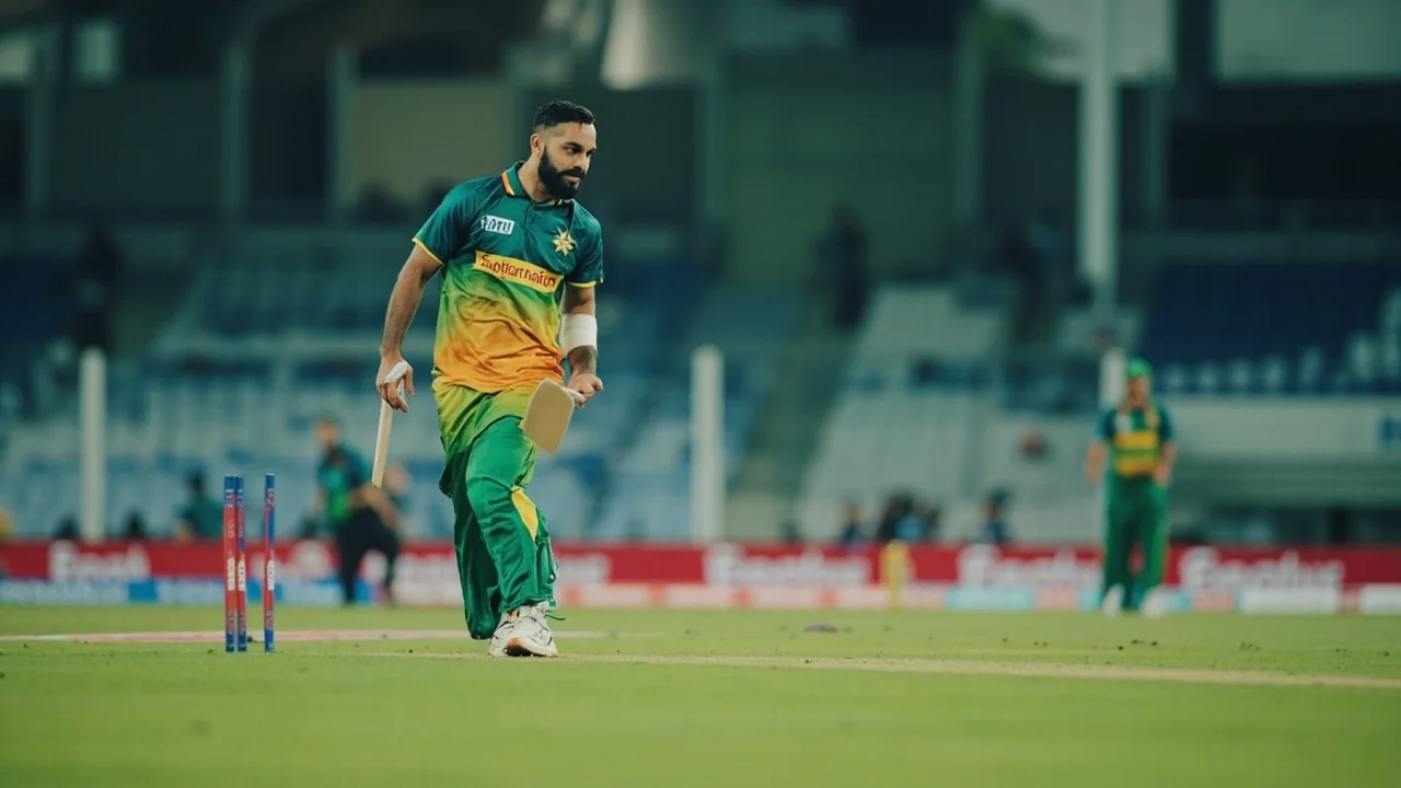 Medium tactical view of field placements at an Asian Games T20 match, with the captain pointing to a deep third-man position and the bowler walking back to his mark under floodlights